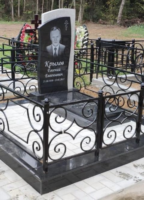 Памятник и ограда на черном гранитном цоколе на кладбище